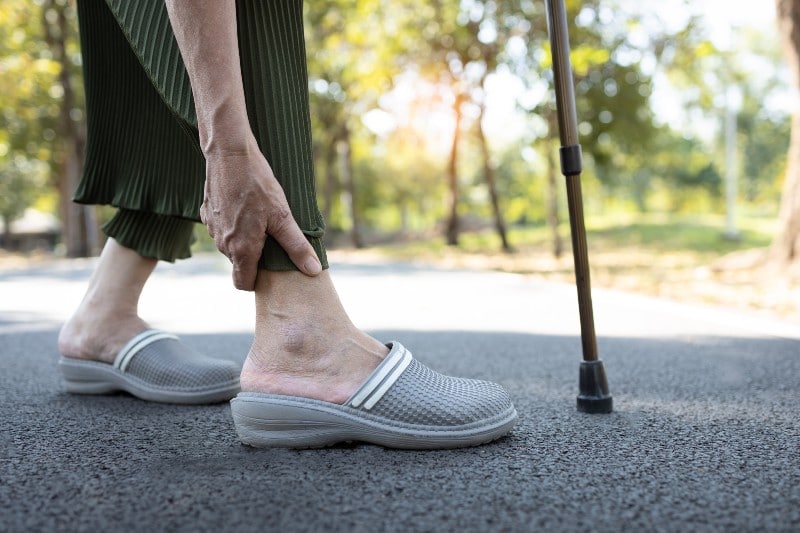 elderly person holding achilles tendon