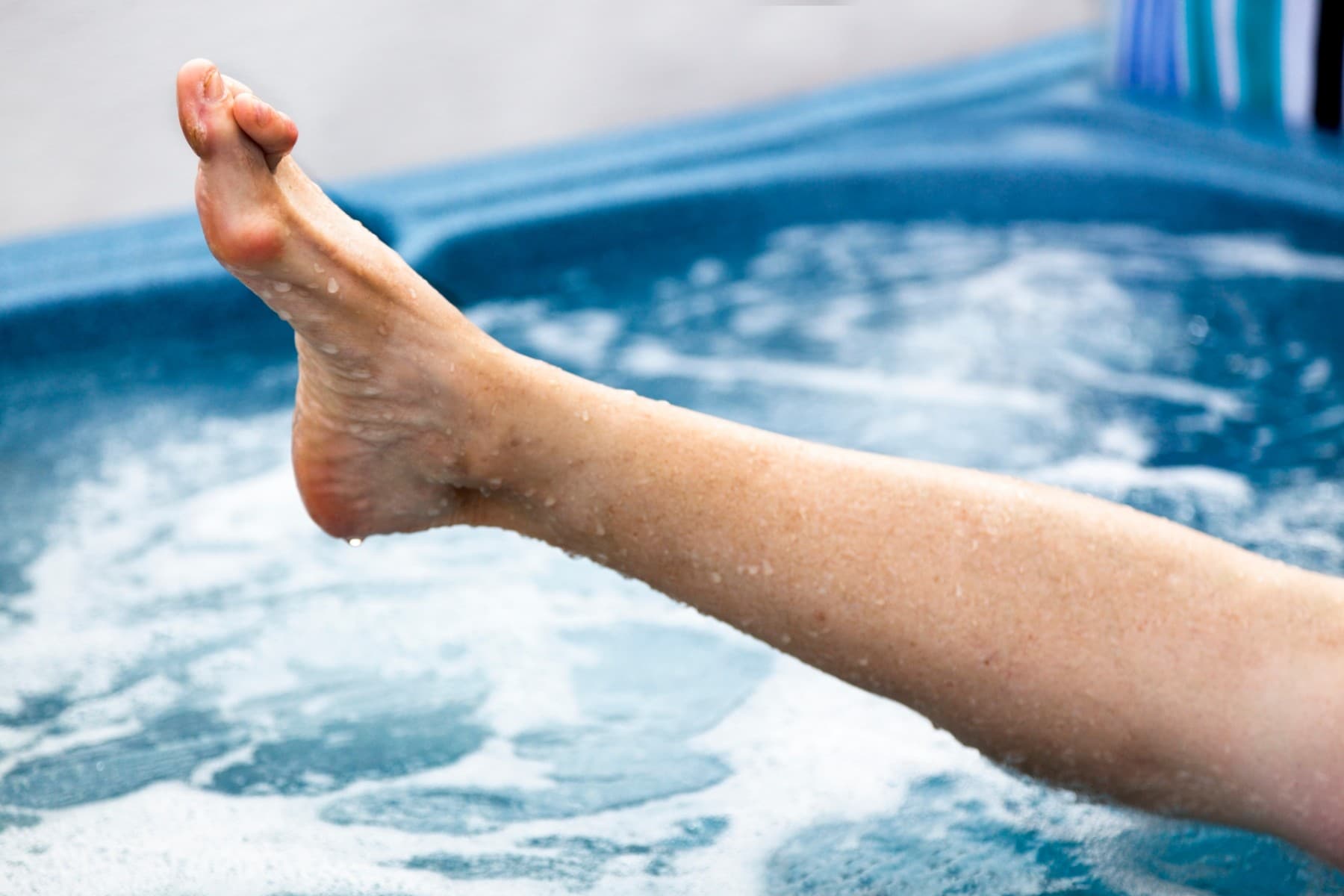 a person sticking their leg out of a hot tub to show their foot that has a hammertoe